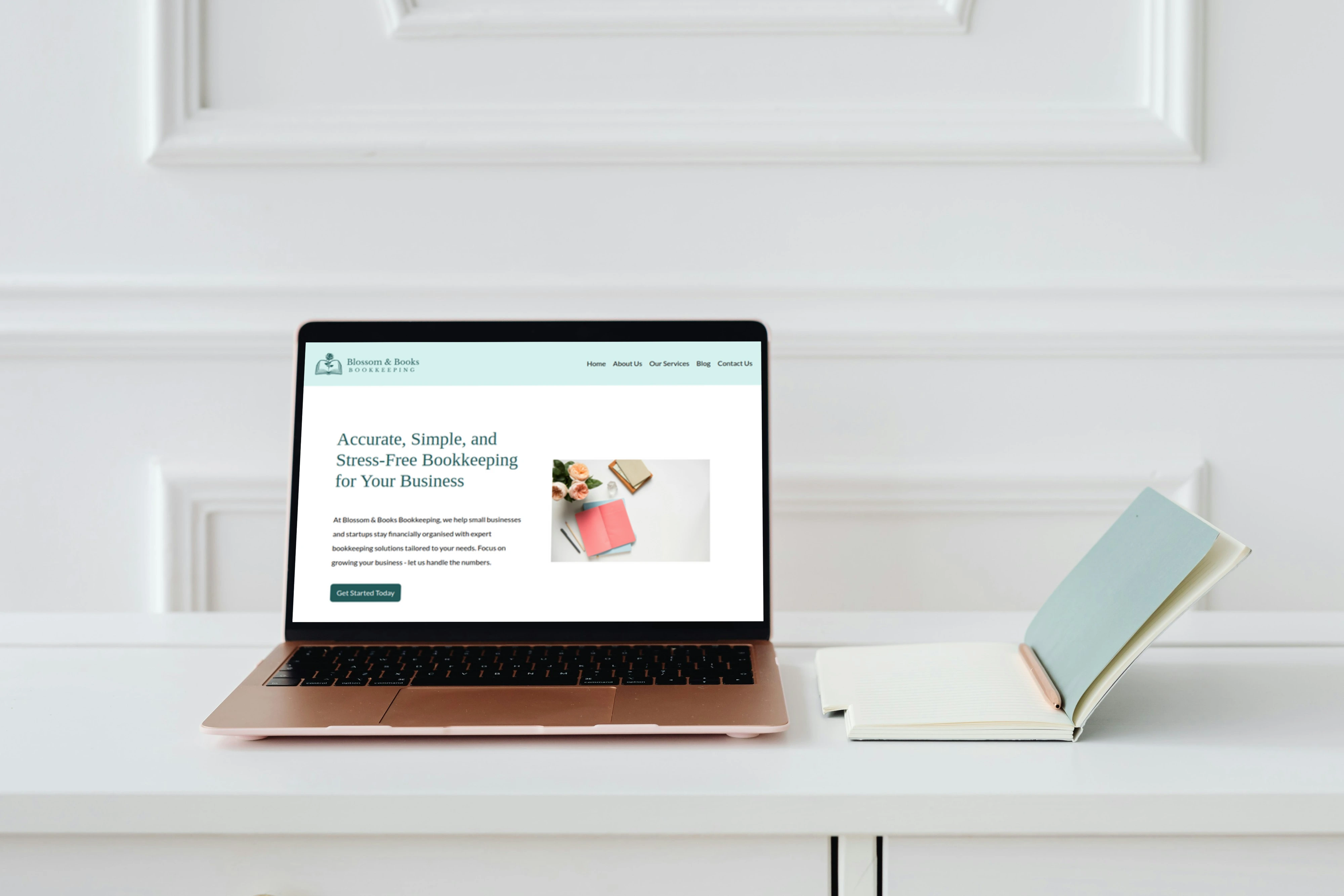 Bookkeeping website shown on a laptop next to a notebook on a white desk.
